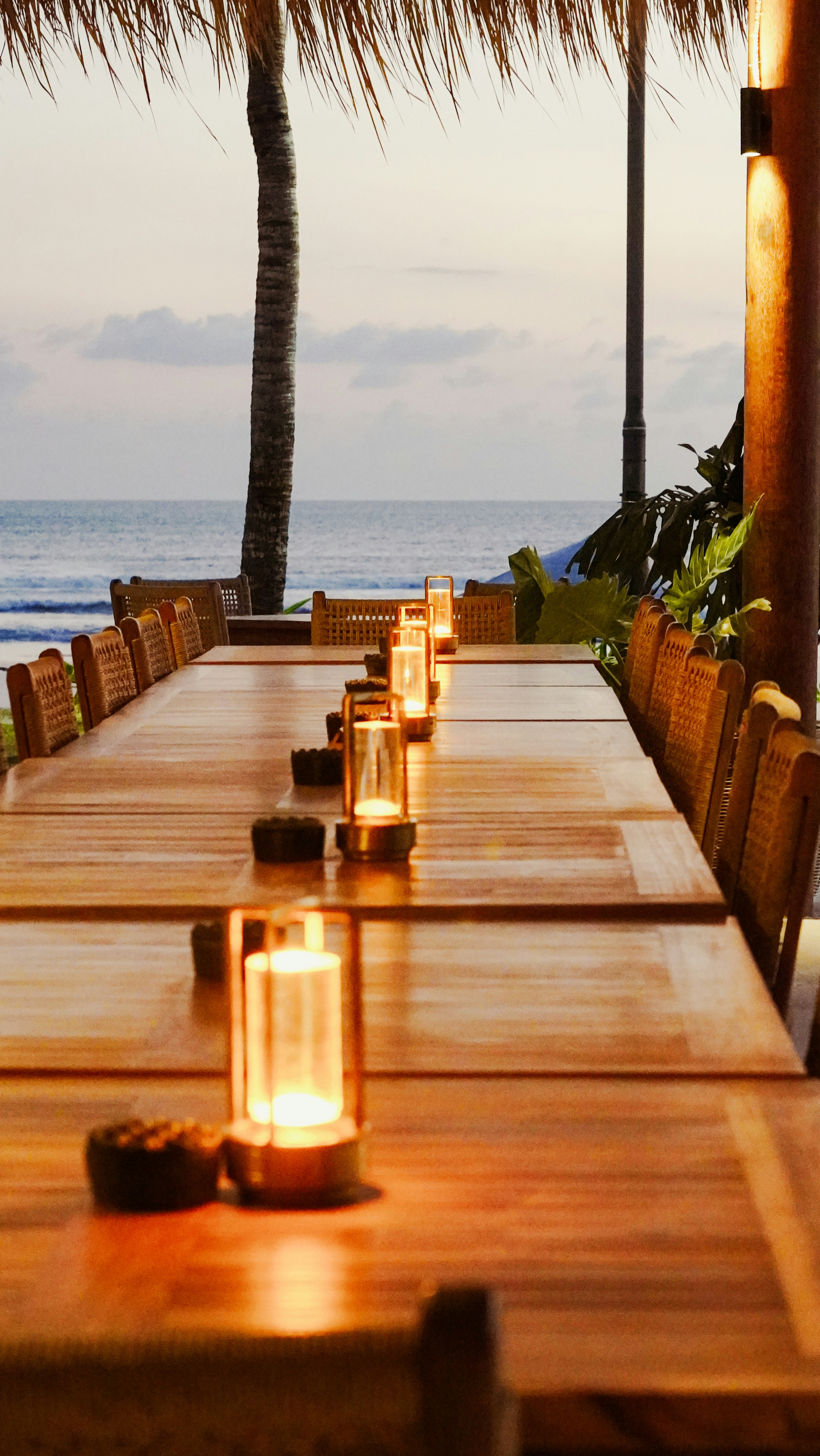 Gedekte tafel met lantaarns aan zee bij zonsondergang